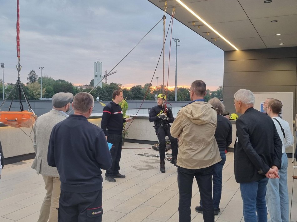 Vorführung der Höhenrettung Teilnehmende des Wirtschaftsstammtisches stehen bei Höhenrettung zu